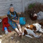 Una mujer se sienta en el suelo con un perro tras ser evacuada de una zona inundada tras el colapso de la presa de Nova Kajovka en el transcurso del conflicto entre Rusia y Ucrania, en la localidad de Hola Prystan, en la región controlada por Rusia de Jer